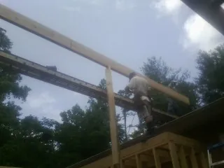 Carpenter setting a ridge beam over a new addition frame — Ice Dam Removal by Roofing Brothers in Monessen
