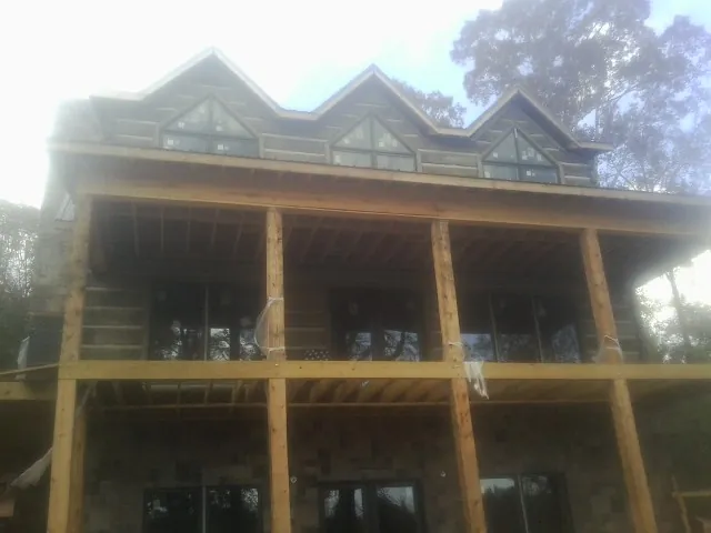 Dormers and porch framing on a large log home under construction — Roof Coating work by our crew in Monessen
