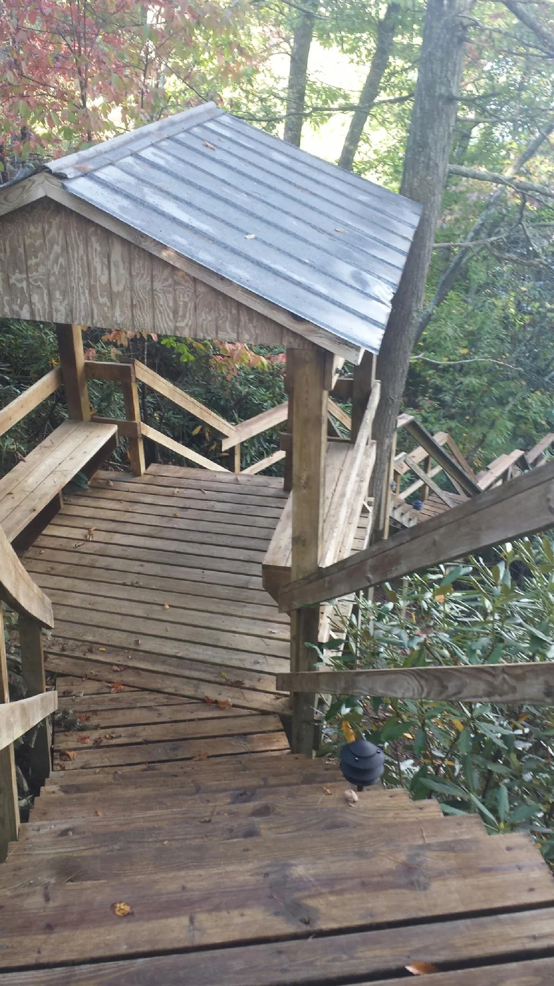 Metal roofed shelter over wooden steps on a wooded walkway — Skylight Repair & Installation work by our crew in Monessen