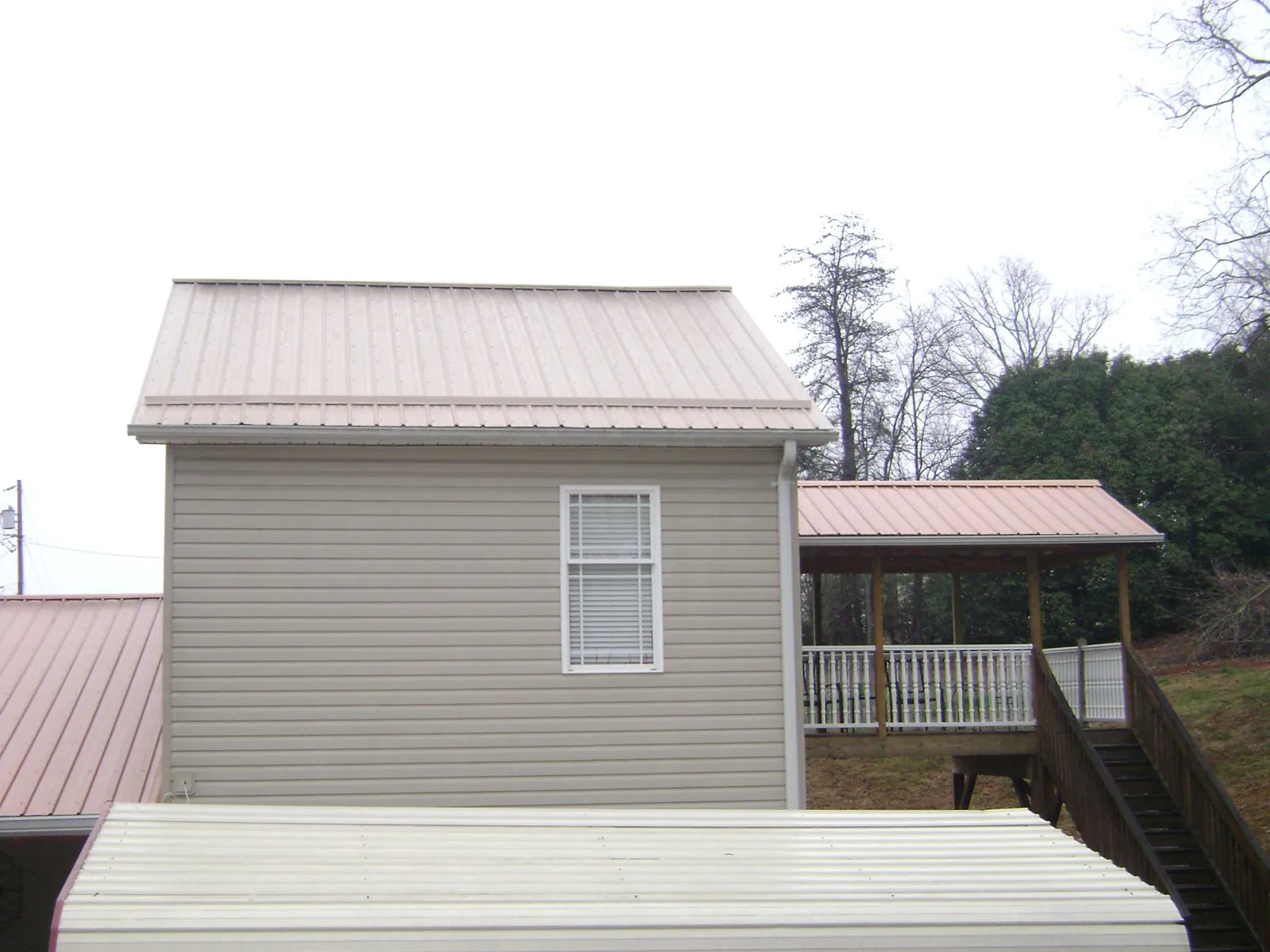 Tan metal roofs on a two story addition and attached porch, from a Roof Replacement job in Monessen