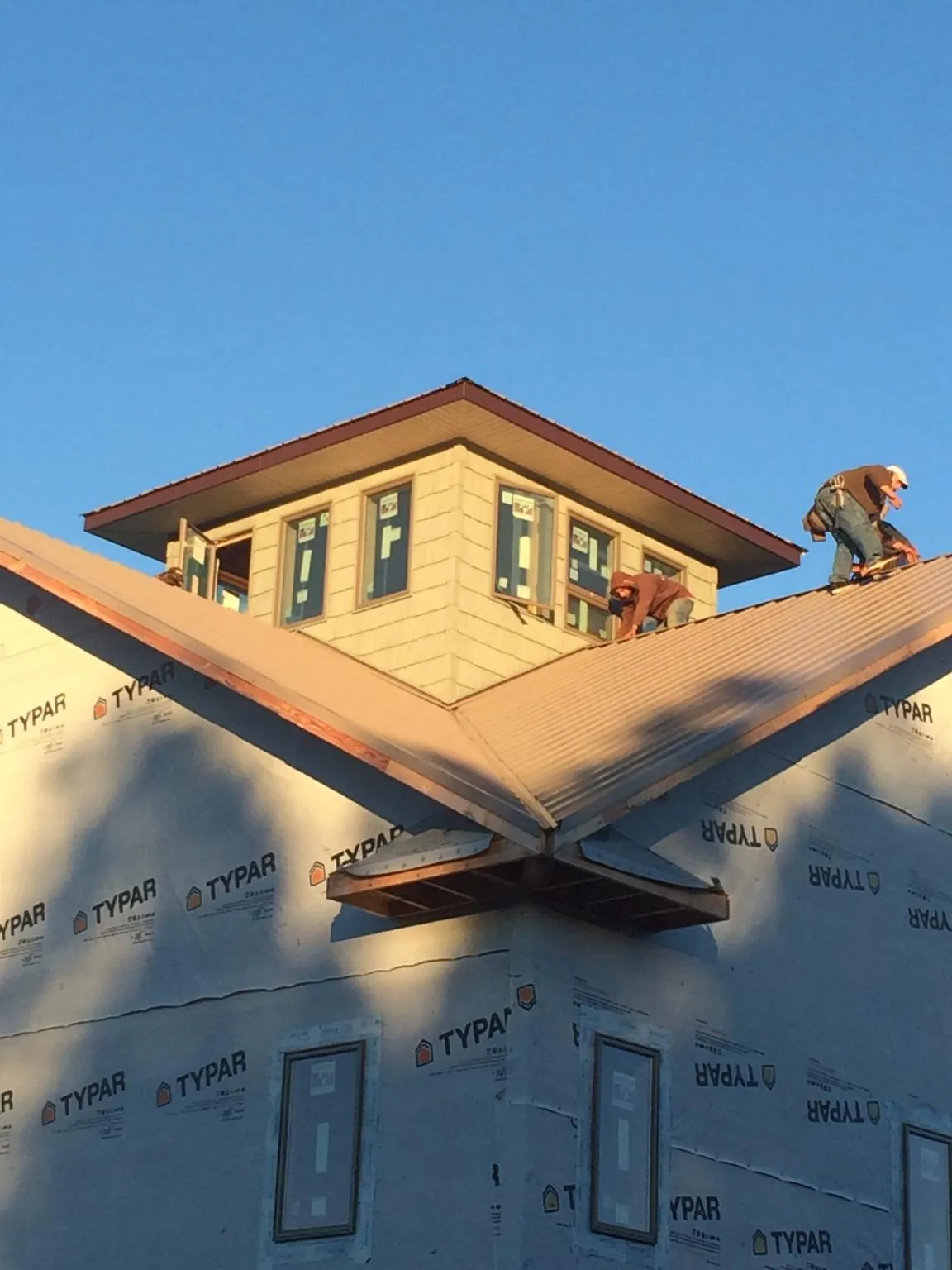 Roofers working around a rooftop cupola on a new metal roof at sunset — Roof Waterproofing in Monessen by Roofing Brothers